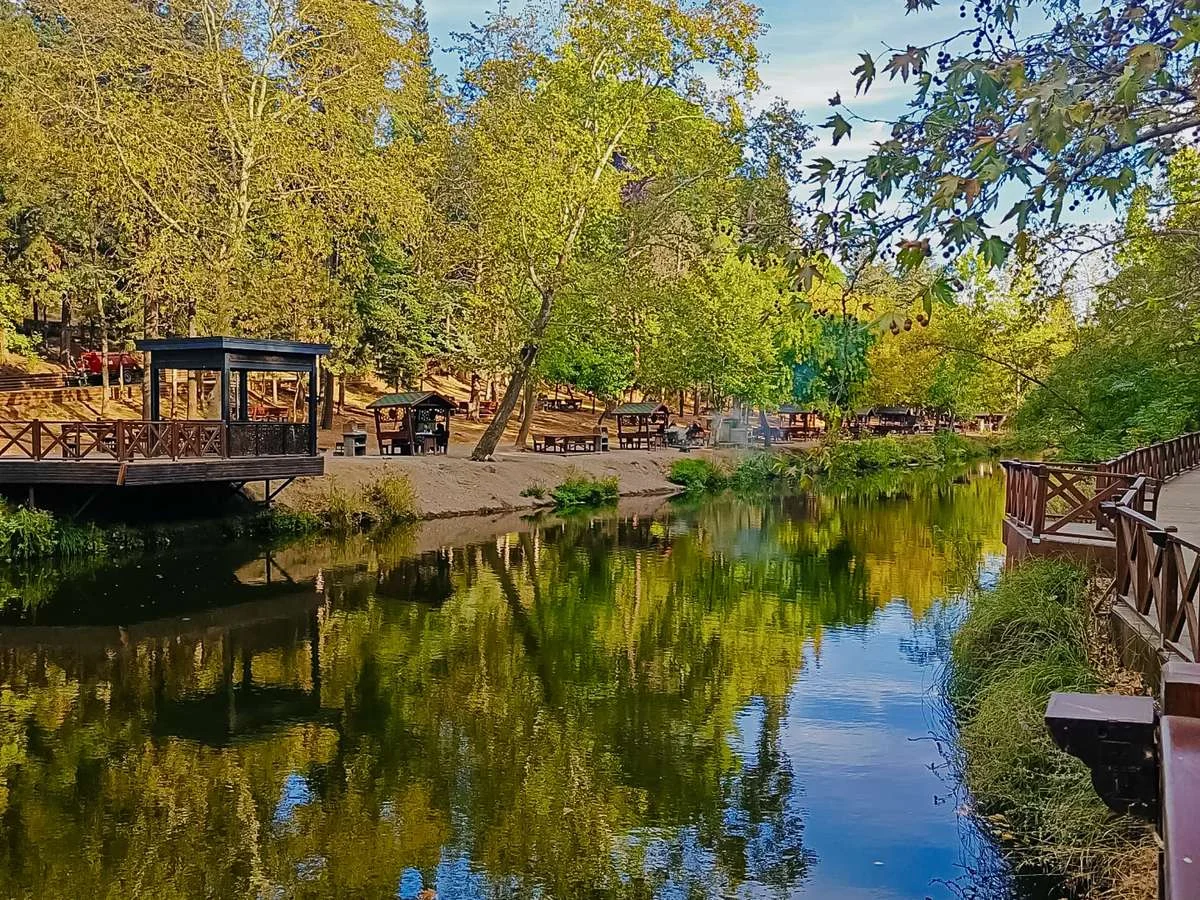 Tabiat Parkı'nda dere kenarına inşa edilmiş ahşap seyir terası ve sıralı oturma alanları.
